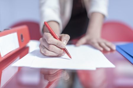 Woman's hand holding ballpen for writing down something in an office